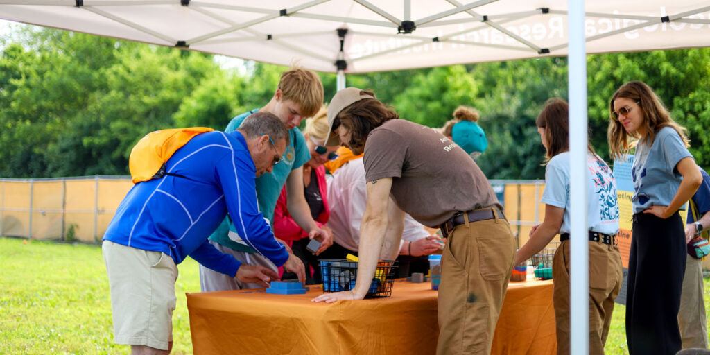 Participants gather around a hands-on archaeology activity station during ARI’s Adventure Trek outdoor community event