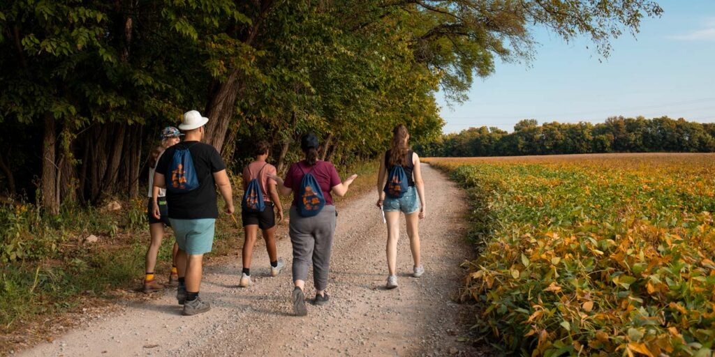 Participants walking along a scenic gravel trail during ARI's Summer Hiking Series at Oxbow Nature Conservancy