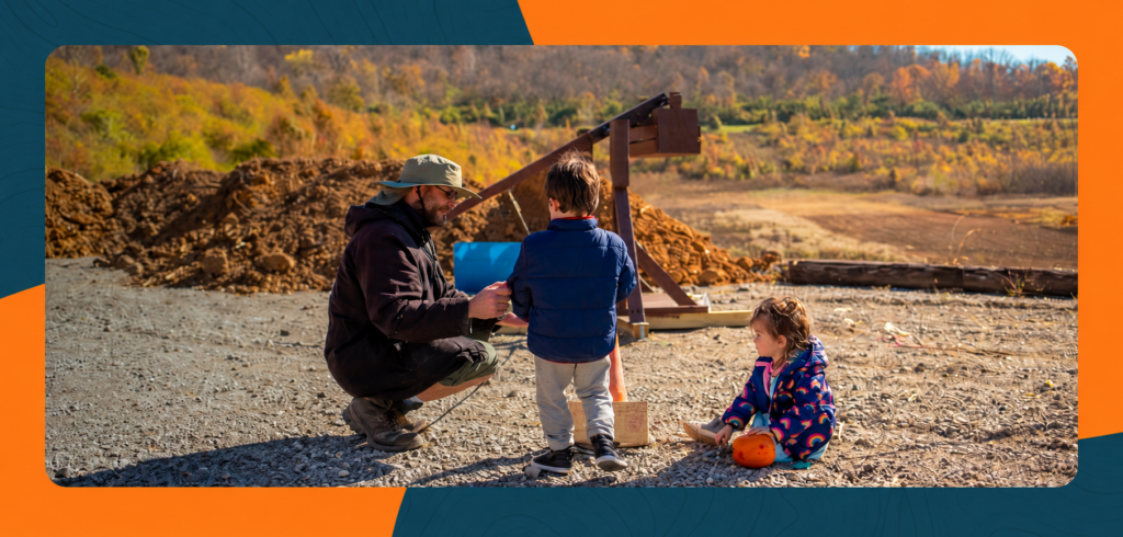 A family explores a wooden trebuchet and pumpkin at ARI’s Pumpkin STEM Festival.
